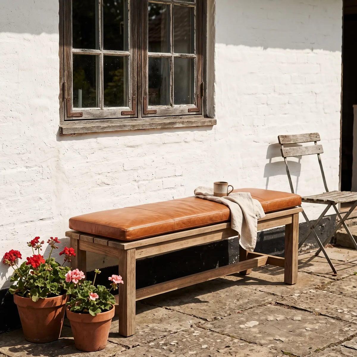 Buffalo Leather Bench Cushion 140 cm on a garden bench against a whitewashed farmhouse wall