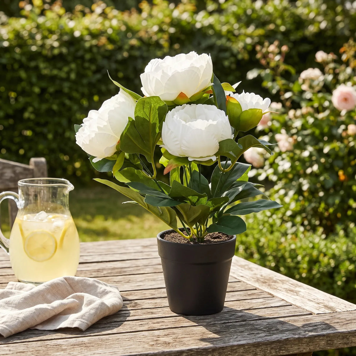 Artificial White Peony in Pot on a garden table beside a jug of lemonade