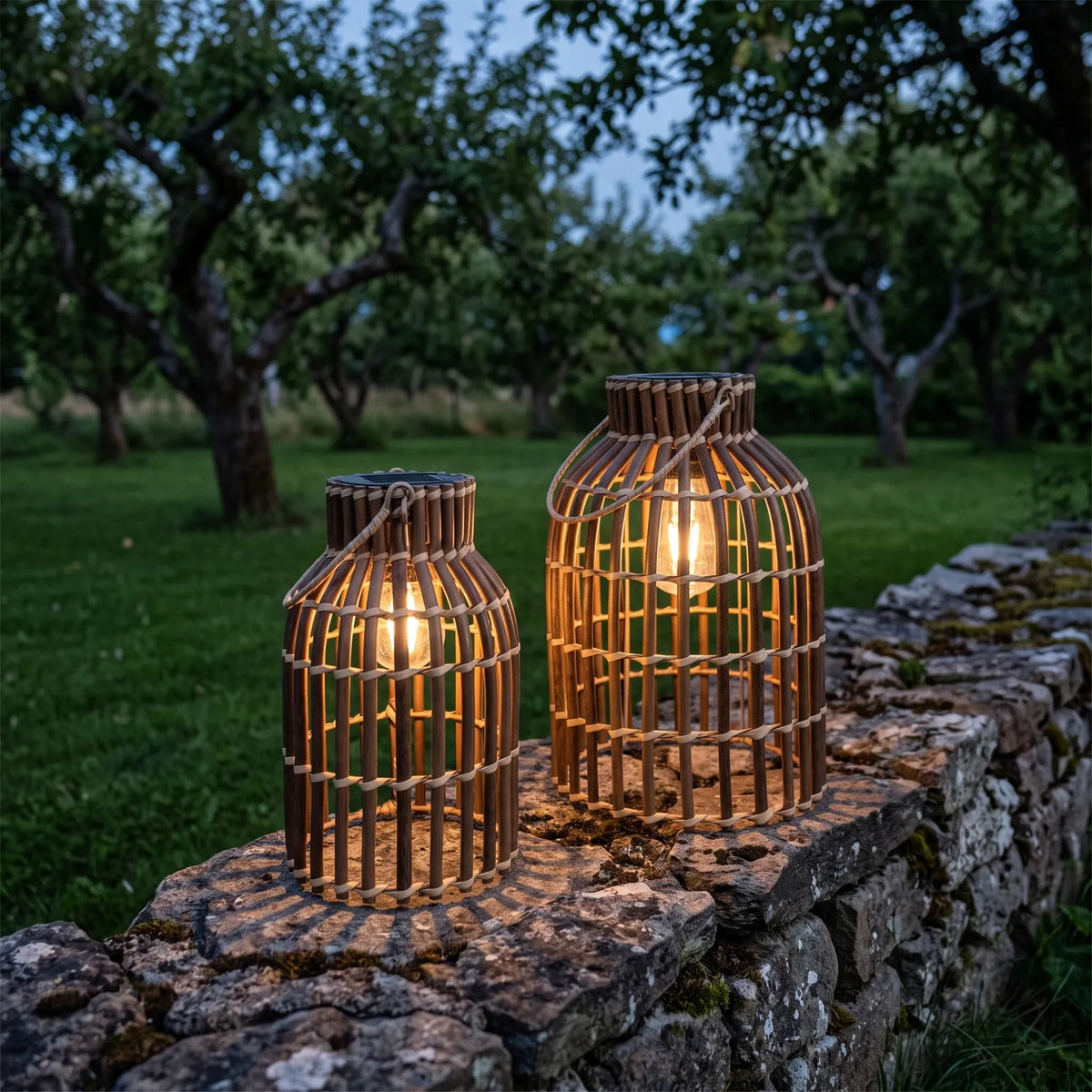 Rattan Lanterns Set of 2 with glowing bulbs on a stone garden wall at twilight